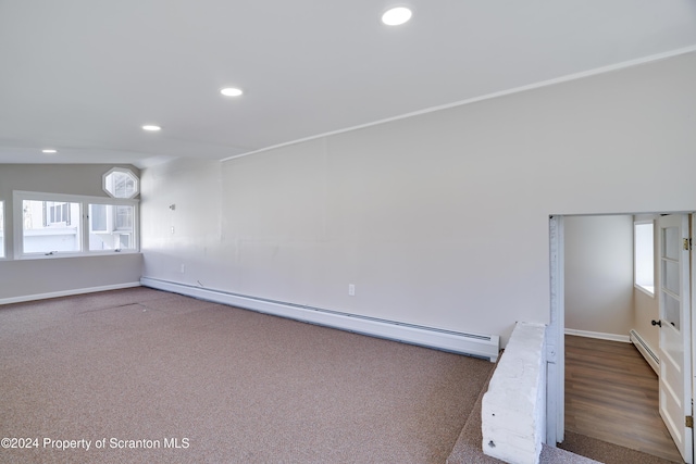 carpeted spare room featuring a baseboard heating unit