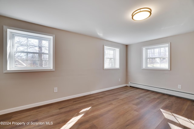 unfurnished room featuring a baseboard radiator, light hardwood / wood-style flooring, and a healthy amount of sunlight