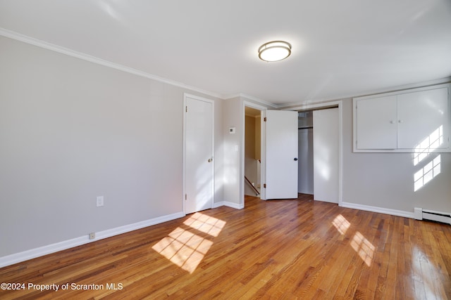 unfurnished bedroom featuring crown molding, a baseboard radiator, and light hardwood / wood-style flooring