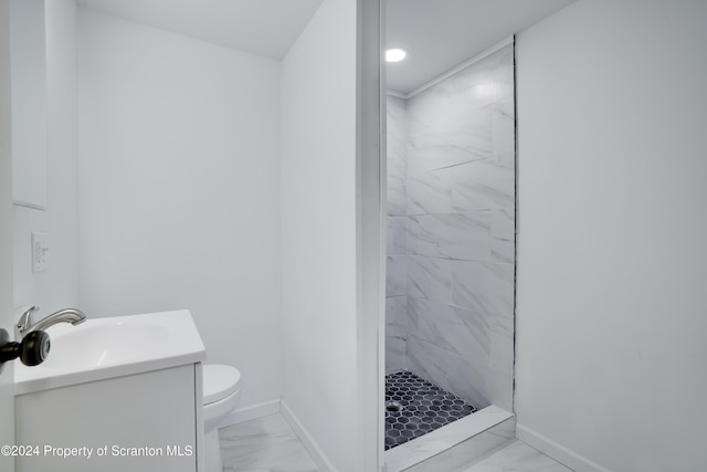 bathroom with a tile shower, vanity, and toilet