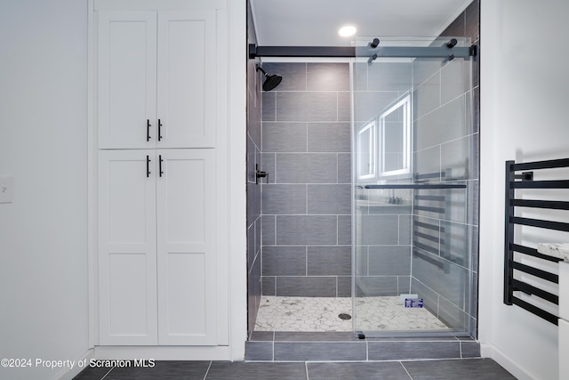 bathroom with tile patterned floors, radiator, and a shower with shower door