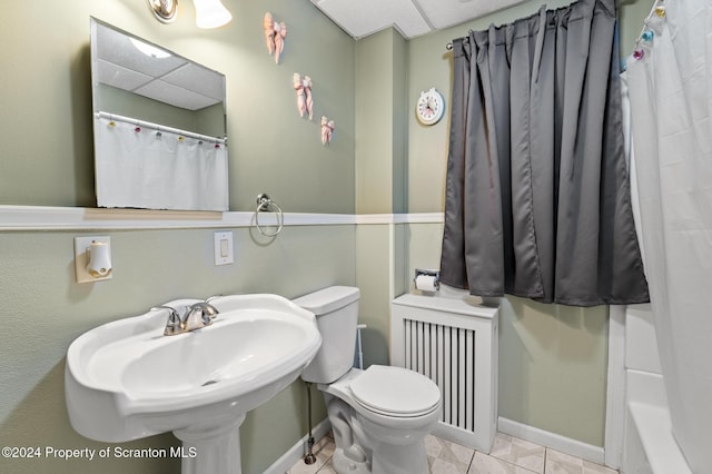 bathroom featuring a drop ceiling, sink, tile patterned flooring, toilet, and radiator heating unit