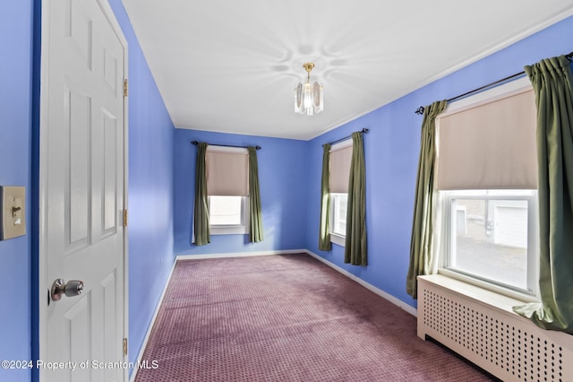 carpeted empty room featuring radiator heating unit and plenty of natural light