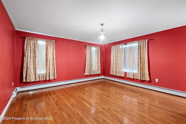 unfurnished room with hardwood / wood-style floors and baseboard heating