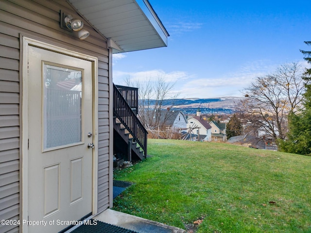 view of exterior entry with a lawn and a mountain view