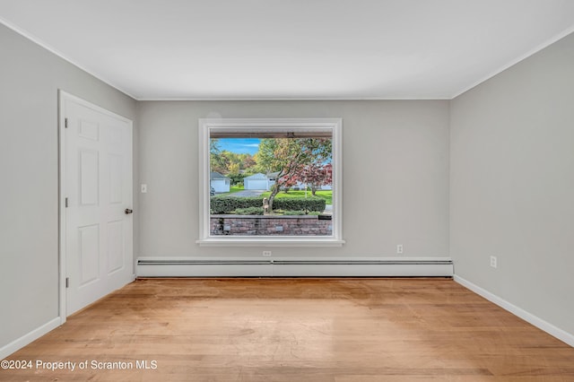 empty room with light hardwood / wood-style floors and a baseboard heating unit