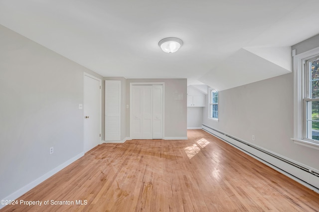 bonus room featuring light wood-type flooring, vaulted ceiling, and a baseboard heating unit