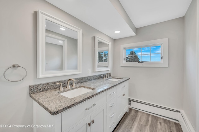 bathroom with vanity, hardwood / wood-style flooring, baseboard heating, and plenty of natural light