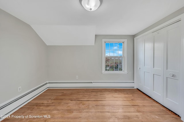 bonus room with a baseboard radiator, lofted ceiling, and light wood-type flooring