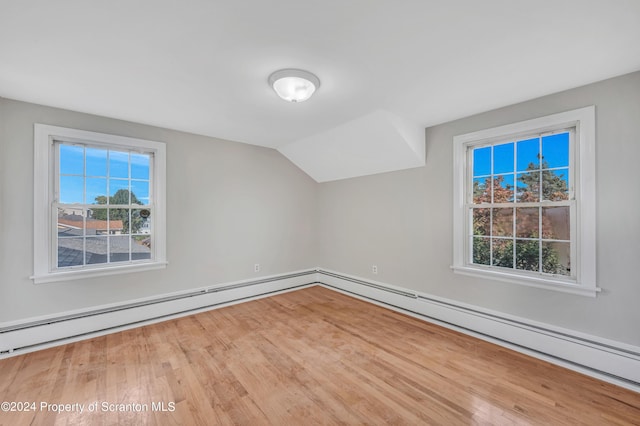 bonus room with lofted ceiling, a baseboard heating unit, and hardwood / wood-style flooring