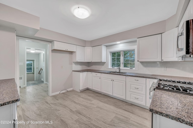 kitchen with dark stone countertops, sink, and white cabinets