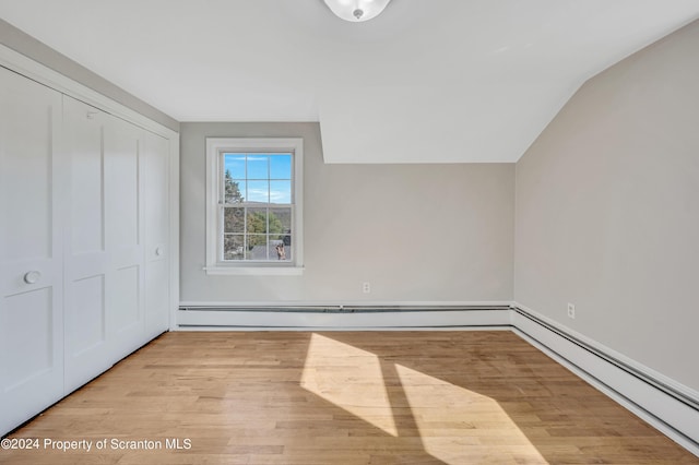 additional living space with vaulted ceiling, light wood-type flooring, and a baseboard radiator