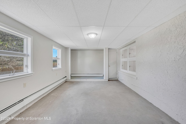 spare room with a paneled ceiling, concrete floors, and a baseboard radiator