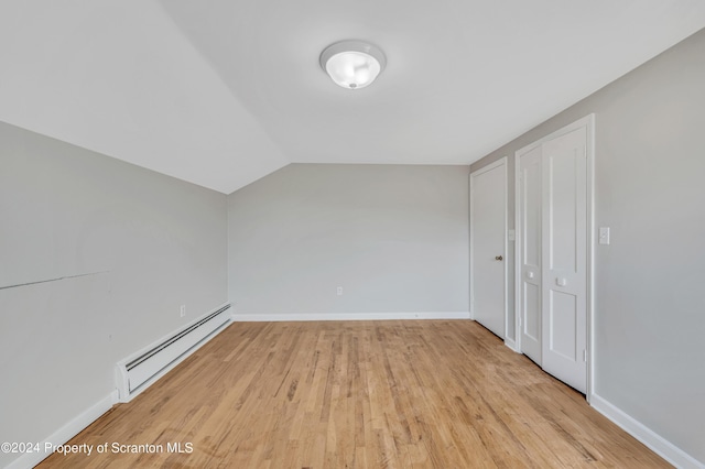 additional living space with lofted ceiling, light hardwood / wood-style flooring, and a baseboard radiator