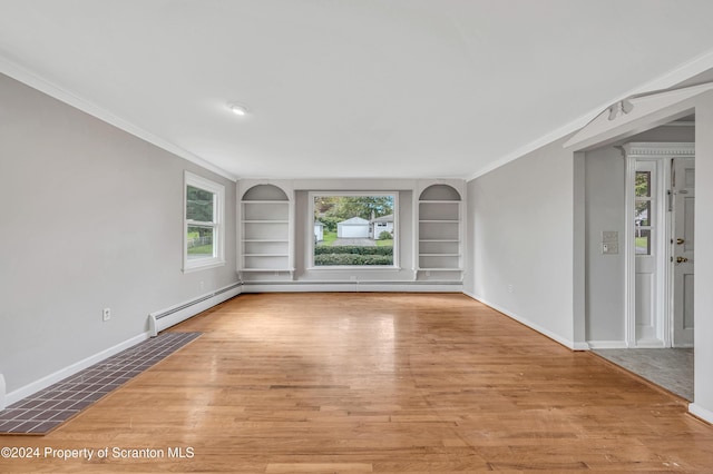 spare room with built in shelves, light wood-type flooring, crown molding, and a wealth of natural light