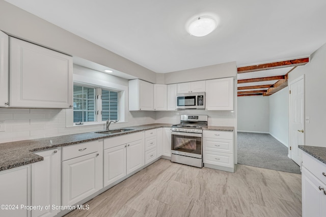 kitchen featuring beamed ceiling, white cabinets, sink, and appliances with stainless steel finishes