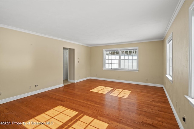 spare room featuring baseboards, wood finished floors, and ornamental molding