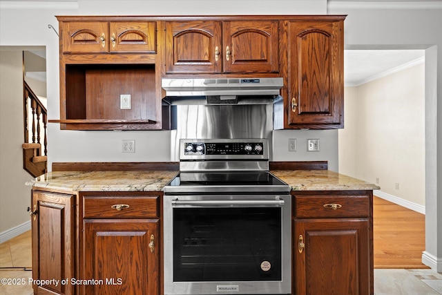 kitchen featuring light stone counters, under cabinet range hood, ornamental molding, brown cabinetry, and stainless steel range with electric stovetop