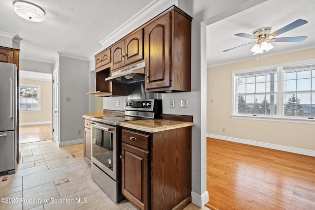 kitchen featuring under cabinet range hood, a ceiling fan, baseboards, ornamental molding, and appliances with stainless steel finishes