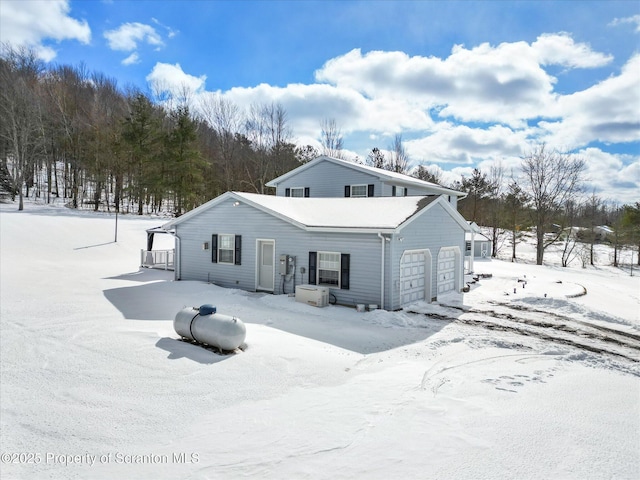 snow covered house featuring a garage