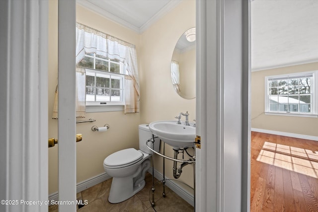 bathroom featuring baseboards, plenty of natural light, toilet, and crown molding