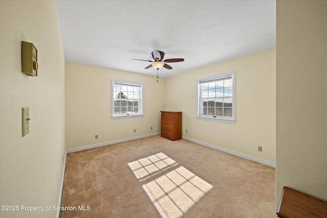 unfurnished bedroom featuring light carpet, ceiling fan, multiple windows, and baseboards