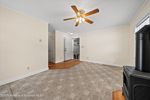 unfurnished living room featuring light carpet, ornamental molding, a wood stove, and baseboards