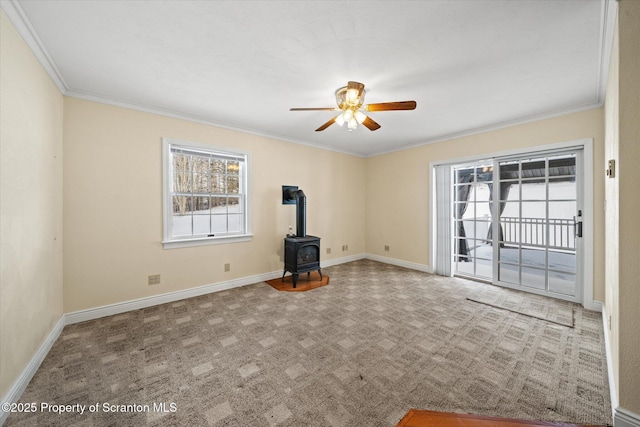 unfurnished living room featuring carpet floors, a wealth of natural light, a wood stove, and a ceiling fan