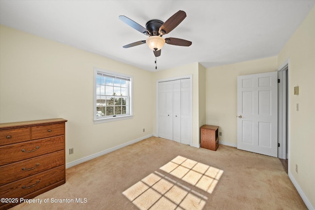 unfurnished bedroom featuring baseboards, ceiling fan, a closet, and light colored carpet