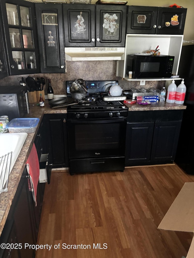 kitchen featuring black appliances, under cabinet range hood, and dark cabinetry