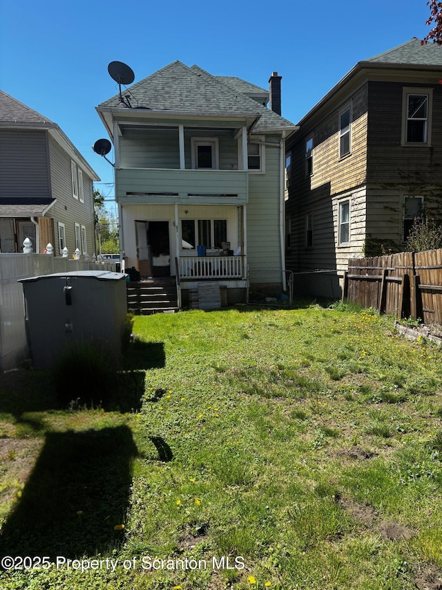 back of house featuring covered porch and a shingled roof