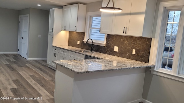 kitchen featuring decorative light fixtures, light stone counters, white cabinetry, and sink