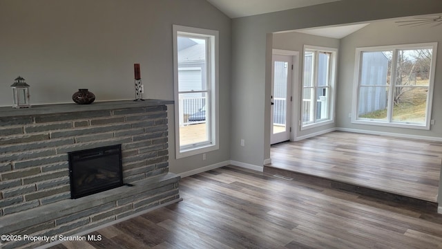 unfurnished living room with ceiling fan, hardwood / wood-style floors, lofted ceiling, and a brick fireplace