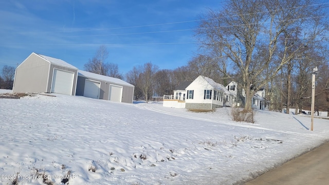 snowy yard featuring a garage and an outdoor structure