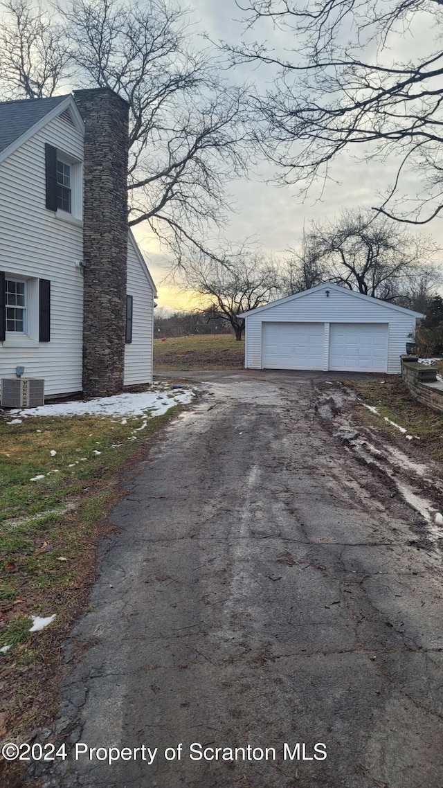 property exterior at dusk with an outbuilding, a garage, and central air condition unit