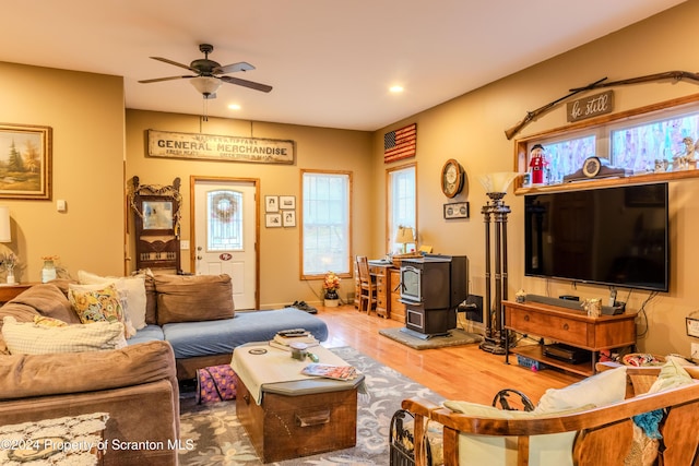 living room featuring hardwood / wood-style floors, a wood stove, and ceiling fan