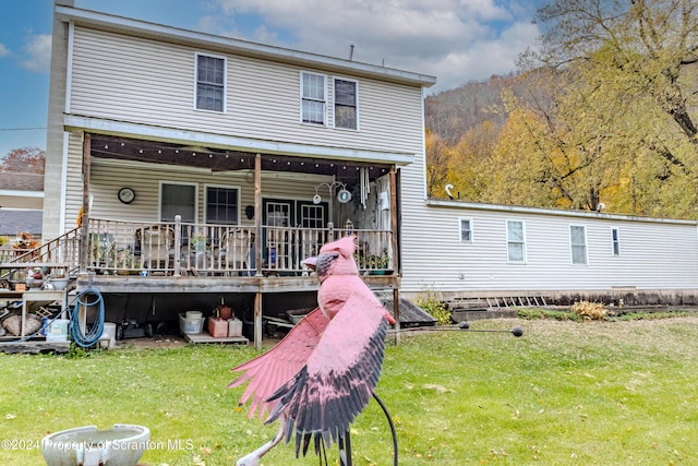 back of house featuring a lawn and a wooden deck