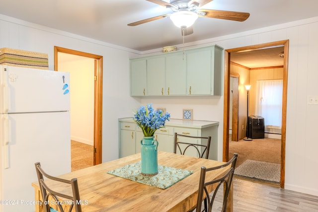 carpeted dining area featuring a baseboard heating unit, ceiling fan, and crown molding