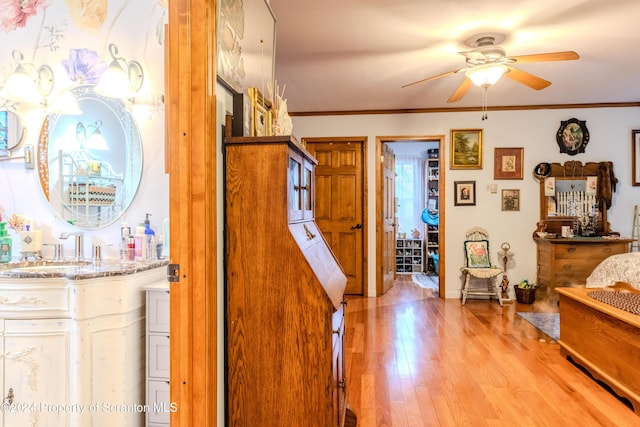 hall featuring light wood-type flooring, ornamental molding, and sink