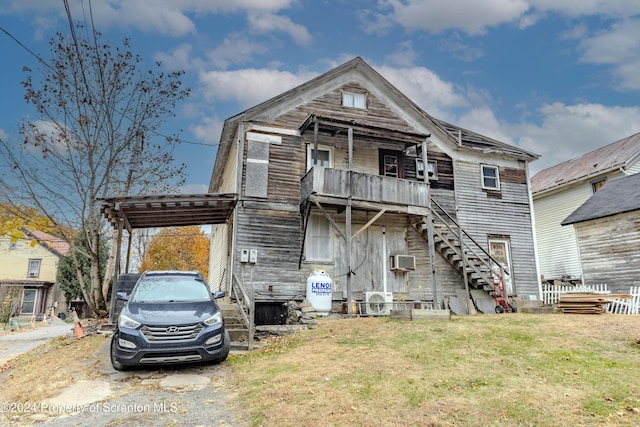 view of front of home featuring a front yard, ac unit, and a balcony