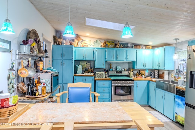 kitchen featuring appliances with stainless steel finishes, vaulted ceiling with skylight, sink, blue cabinetry, and hanging light fixtures