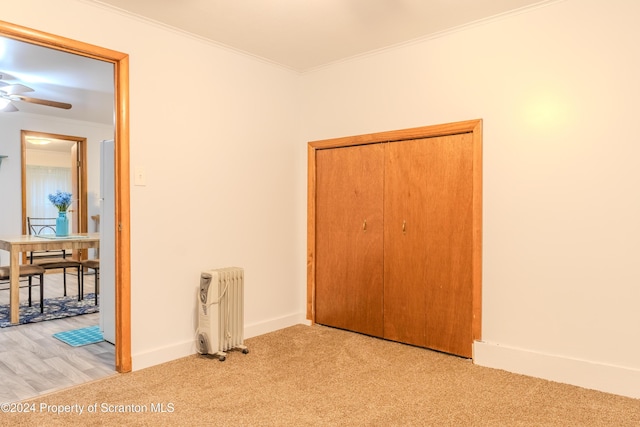 unfurnished bedroom with radiator heating unit, light colored carpet, and crown molding