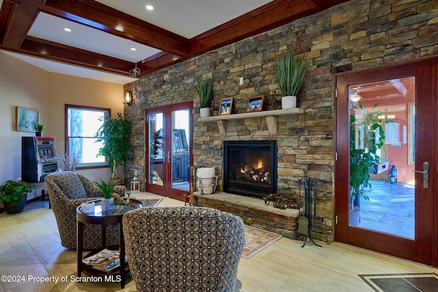 living room with beam ceiling, a stone fireplace, and french doors