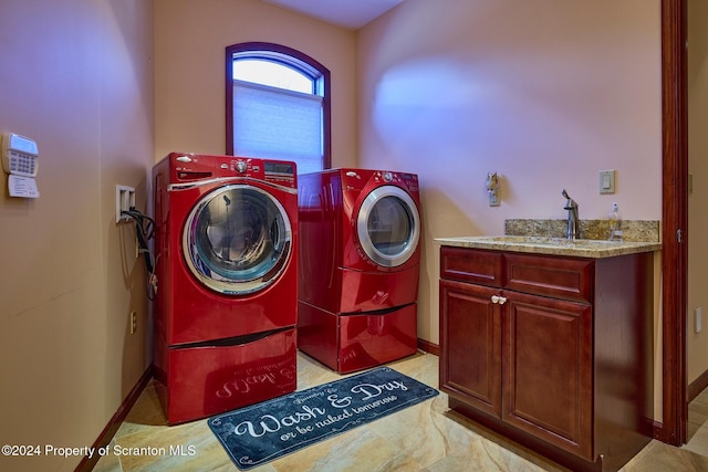 washroom with cabinets, independent washer and dryer, and sink