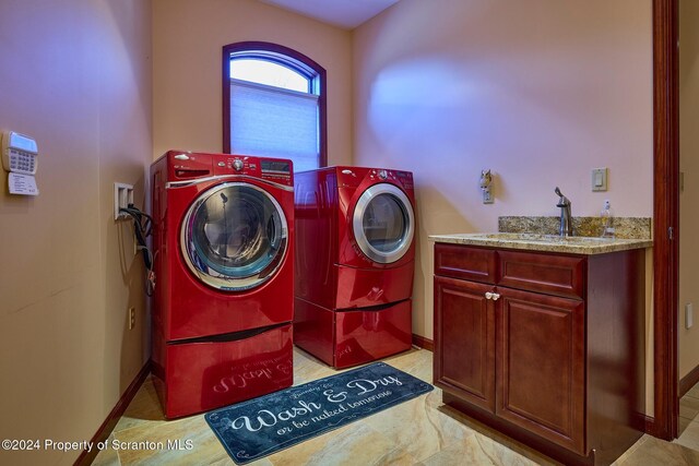 washroom with cabinets, independent washer and dryer, and sink