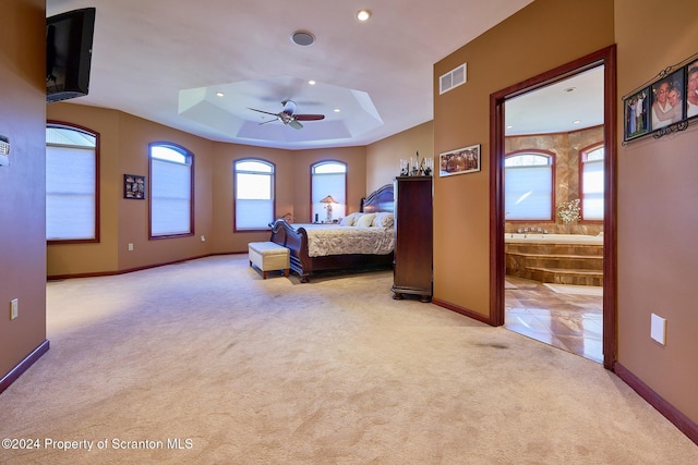 carpeted bedroom with ceiling fan, connected bathroom, and a tray ceiling