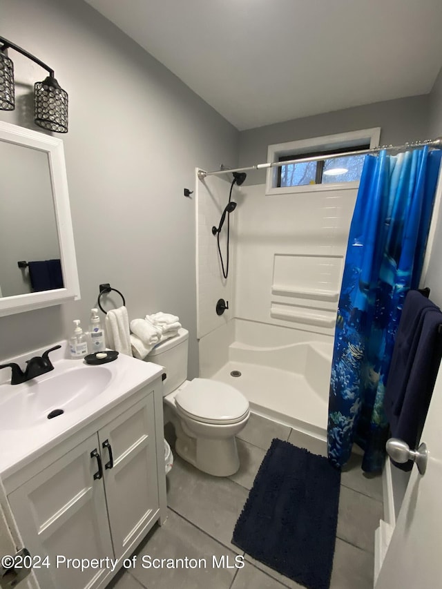 bathroom with tile patterned floors, toilet, vanity, and walk in shower