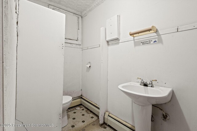 bathroom with baseboard heating, tile patterned flooring, and toilet