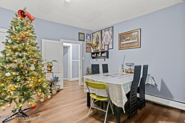 dining space featuring baseboard heating and light hardwood / wood-style flooring