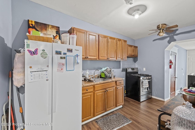 kitchen with dark hardwood / wood-style flooring, ceiling fan, sink, white refrigerator, and stainless steel range with gas cooktop